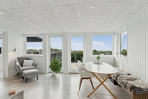 A modern interior with a dining table, chairs, a bench, a sofa, and a potted plant.