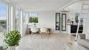 Ein geräumiges Zimmer mit großem Esstisch, zwei Stühlen, einer Couch und einer Küchenzeile.