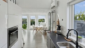 Eine moderne Küche mit Essbereich, großen Fenstern und Blick ins Freie.