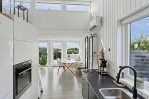 A modern kitchen with a dining area, large windows, and a view of the outdoors.