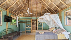 Een kamer met een bed, een bank, een televisie en een plafondventilator.