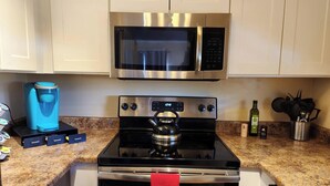 A kitchen with a stainless steel microwave, a coffee maker, a kettle, and a dishwasher. - Charming 1-bed apt, cook-ready kitchen, laundry,5-8 mins to U of A and Downtown (Tucson)