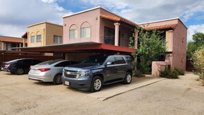 A residential building with a covered driveway, a parked SUV, and a sedan. - Charming 1-bed apt, cook-ready kitchen, laundry,5-8 mins to U of A and Downtown (Tucson)