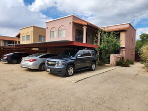 A residential building with a two-story structure, a covered driveway, and parked cars.