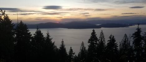 A panoramic view of a lake surrounded by mountains and dense forest.