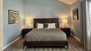 Una camera da letto con un letto grande, due comodini con lampade, un quadro appeso al muro e una finestra con tende.