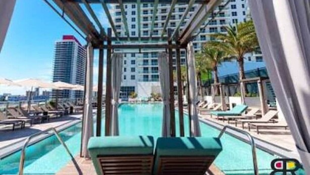 A rooftop pool area with lounge chairs and a view of a high-rise building.