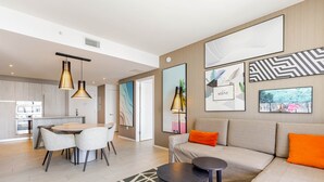 A modern living room with a sofa, two round tables, and a dining area with chairs.