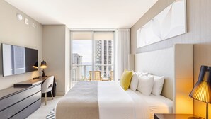 A modern hotel room with a large bed, a desk, and a TV.