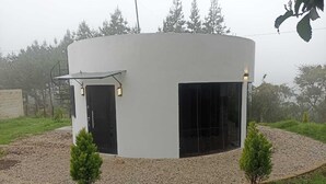 A modern, circular building with a flat roof, a door, and windows. - Camino a Tlacolulan (Las Vigas de Ramirez)