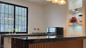 A modern kitchen with a marble countertop, wooden paneling, a built-in stove, and pendant lighting. - Camino a Tlacolulan (Las Vigas de Ramirez)