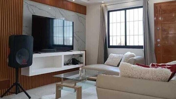 A modern living room with a flat-screen TV, a sofa, a coffee table, and a wooden accent wall. - Camino a Tlacolulan (Las Vigas de Ramirez)