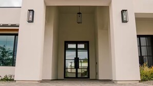 A modern building with a flat facade, large glass entrance, and two wall-mounted lights. - The Showstopper Scottsdale (Scottsdale)