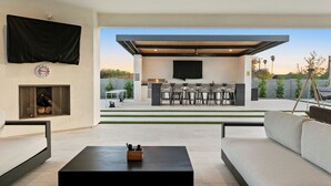 A modern outdoor living area with a fireplace, seating, and a bar setup. - The Showstopper Scottsdale (Scottsdale)