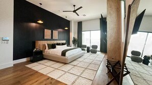A modern bedroom with a large bed, a ceiling fan, and a view of the city through large windows. - The Showstopper Scottsdale (Scottsdale)