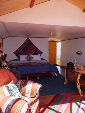 A cozy, well-lit bedroom with a bed, a small table, and a chair.