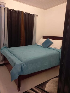 Ein Schlafzimmer mit Bett, Vorhängen und einem hölzernen Kopfteil.