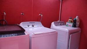 A laundry area with two washing machines, a water heater, and a detergent bottle. - Soothing 2-bedroom apartment with AC (GEORGETOWN)