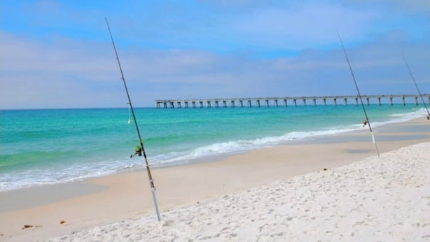 A beach with fishing rods and a pier in the background.