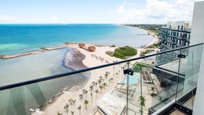 A beachfront hotel with a view of the ocean, beach umbrellas, and a pool area. - Breathtaking 2BR deluxe condo with stunning views (Progreso)