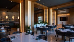 A spacious restaurant with high ceilings, modern lighting, and a variety of seating arrangements. - Breathtaking 2BR deluxe condo with stunning views (Progreso)