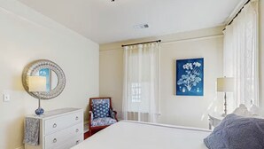 A bedroom with a large bed, a dresser, a chair, a mirror, and a painting on the wall.