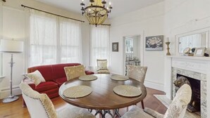 Een eetkamer met een ronde tafel, een rode bank en witte stoelen.