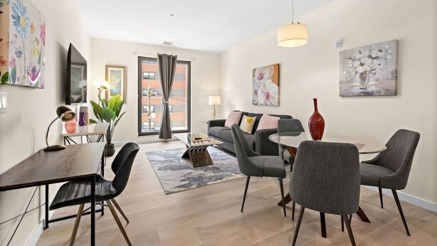 A modern living room with a sofa, chairs, a dining table, and artwork on the walls.