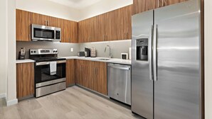 A modern kitchen with wooden cabinets, stainless steel appliances, a microwave, oven, and a refrigerator.