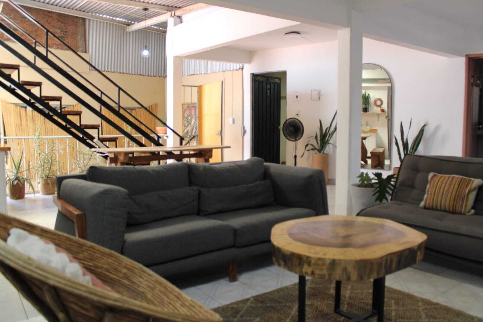 A spacious living room with a grey sofa, a round wooden coffee table, and a staircase leading to an upper level.