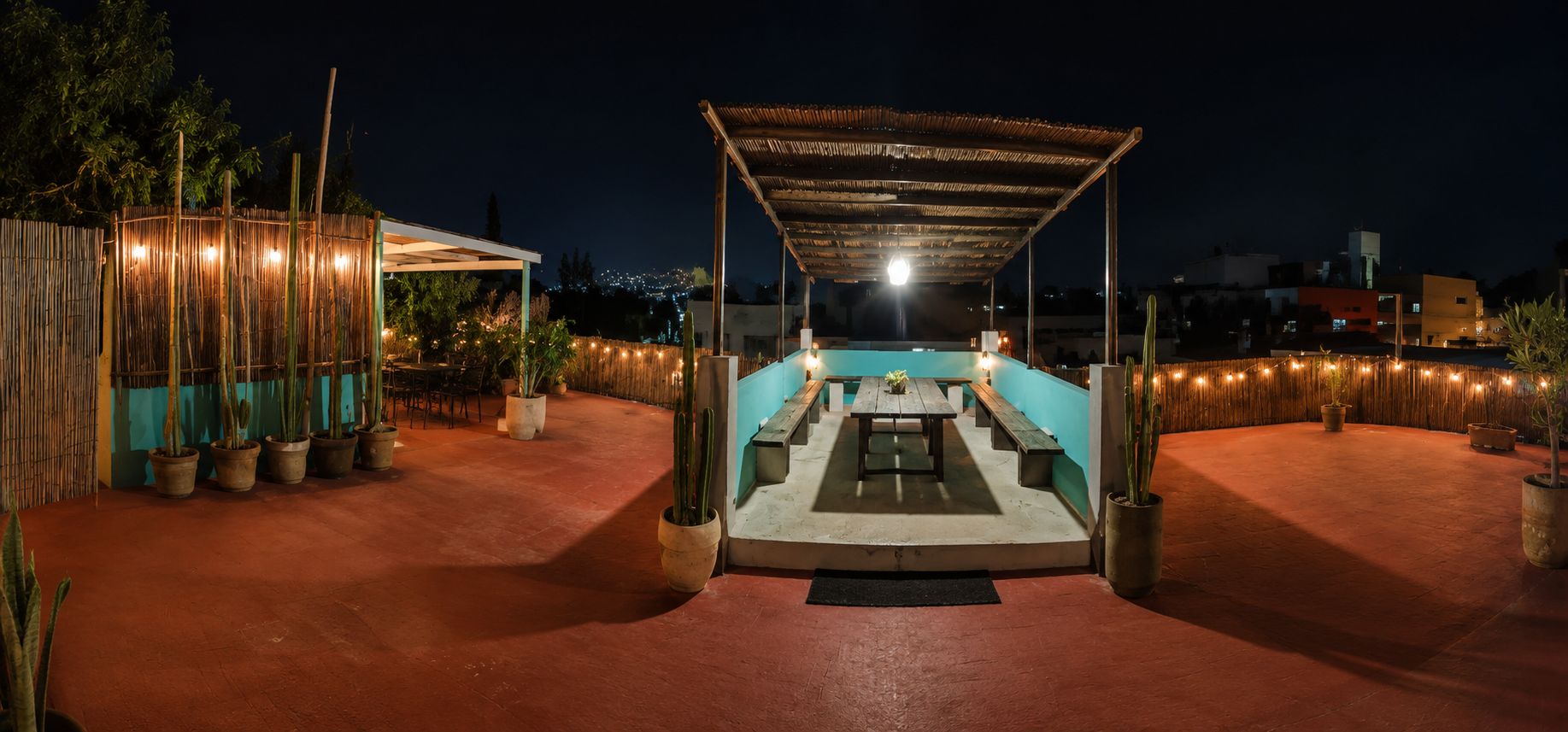 An outdoor patio area with a pool, surrounded by potted plants and a bamboo fence.