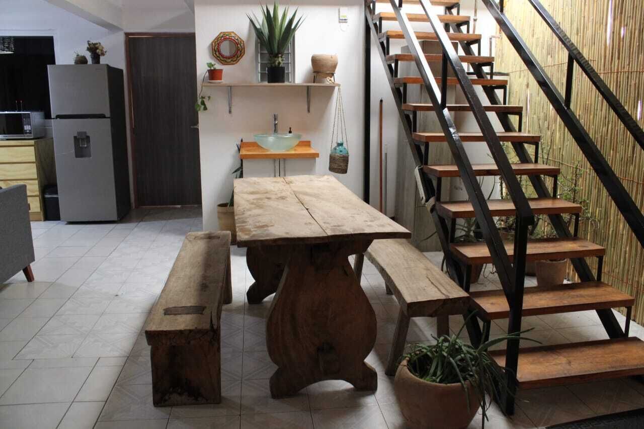 A kitchen with a wooden table and bench, a staircase, and a sink.