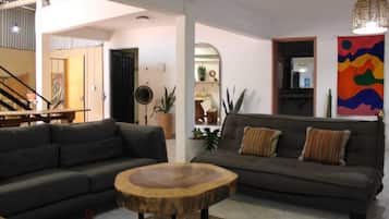 A living room with two sofas, a round wooden coffee table, and a colorful abstract painting on the wall.