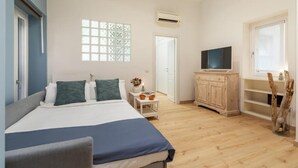 Un dormitorio con cama, televisor, ventana y armario de madera.