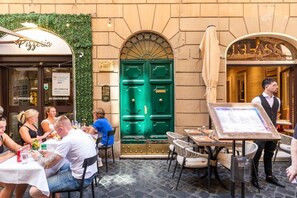 An outdoor cafe with tables and chairs, a green door, and a menu board.