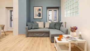 Un salón moderno con un sofá seccional gris, una mesa de centro blanca y una ventana con paneles de vidrio decorativos.