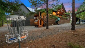 A disc golf basket with chains and a wooden structure in the background.