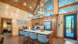 A spacious kitchen with wooden cabinets, a large island with bar stools, and modern appliances.