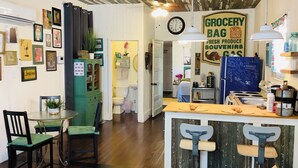 A kitchen with a central island, bar stools, a green cabinet, and a clock on the wall.