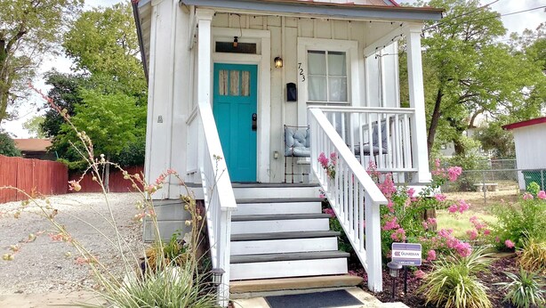 A small white building with a turquoise door and a porch.