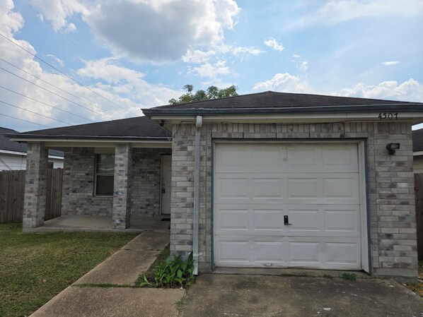 A two-story house with a garage, brick exterior, and a small front yard.