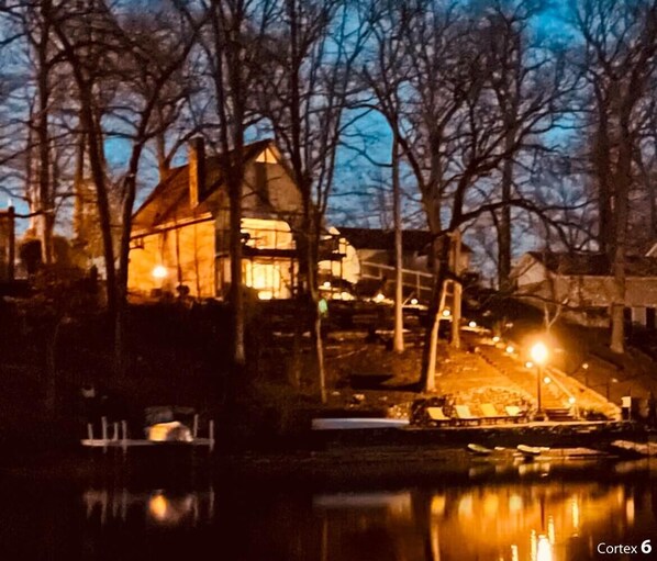 Una casa con una ventana iluminada y un reflejo en el agua.