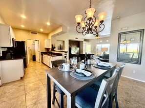 A spacious kitchen with modern appliances, a dining area with a chandelier, and a large mirror on the wall.