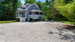A large house with a covered porch, a driveway, and a well-maintained lawn. - Heron's Hideaway - A Trusted Guest Favorite for Spacious Comfort! (Chincoteague Island)