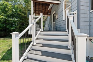 A wooden staircase with white railings leading to a porch with a wooden roof.