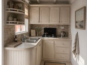 Une cuisine dotée de meubles blancs, d’une cuisinière à gaz, d’un évier et d’une fenêtre offrant une belle vue.