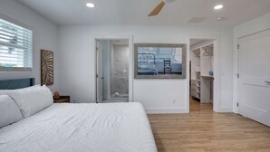 A bedroom with a bed, a ceiling fan, a walk-in closet, and a shower. - Drift and Dune Beach, Pet Friendly, Steps to Beach (Ponce Inlet)