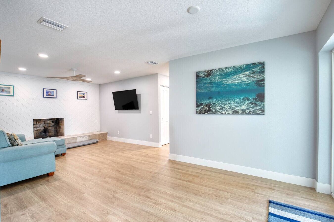 A modern living room with a fireplace, a mounted TV, and a large painting on the wall.