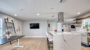 A modern kitchen with a marble island, white cabinetry, and a built-in oven. - Drift and Dune Beach, Pet Friendly, Steps to Beach (Ponce Inlet)