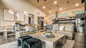 A modern living room with a sofa, coffee table, and a dining area.